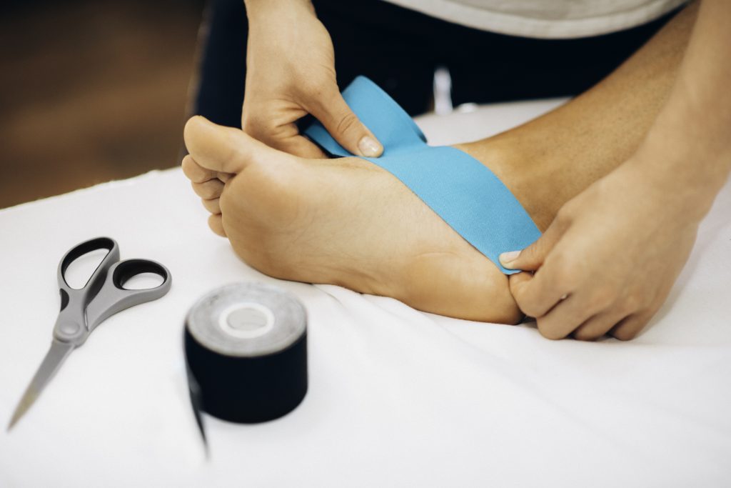 Therapeut legt een taping aan, aan de voet